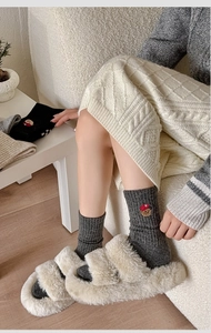 Detailed embroidery of a cute cartoon bear with red cap on thick dark grey wool socks