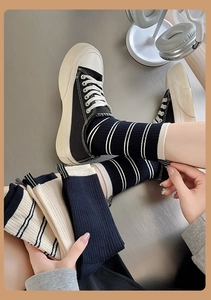 Close-up of black and white striped crew socks paired with casual canvas sneakers