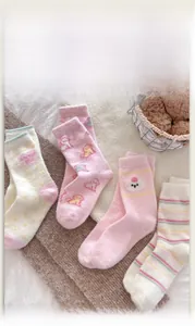 Nahaufnahme von vier Paar dicken rosa und cremefarbenen Korallenvlies-Socken mit süßer Stickerei