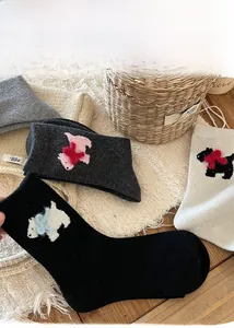 Detail of wool blend puppy socks with 3D bow accents in cozy home setting