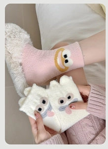 Detail of soft coral fleece socks featuring cute cartoon monster faces and warm texture