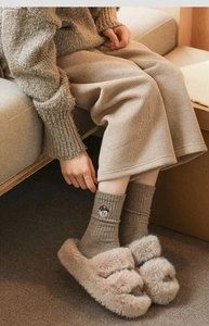 Detail of wool socks with bear embroidery and plush slippers in earth tones