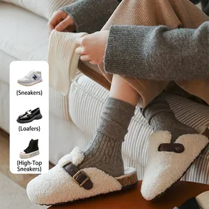 Plush cream shearling mule slippers with brown leather buckle and cork sole detail
