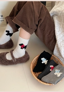 Detailed knit texture of wool socks featuring cute dog patterns and 3D bow accents