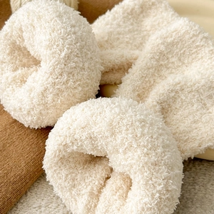 Plush cream faux fur hair scrunchies displayed on cozy textured knitted background