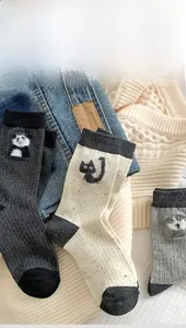 Detailed view of three pairs of knit mid-calf socks with cute animal embroidery patches
