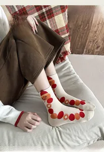 Dettaglio di calze festive color crema con pois rossi e ricamo danza del leone