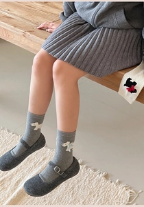Close-up of grey wool socks featuring white dog embroidery and ribbed knit texture