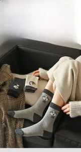 Detail of grey crew socks featuring cute cartoon dog embroidery and ribbed knit cuffs
