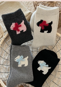 Close-up of winter wool socks featuring cute Westie dog embroidery in a metal basket