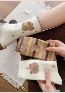 Detail of plush thermal socks with cute bear embroidery and retro stripe patterns