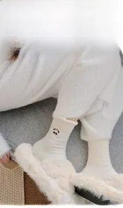 Dettaglio di calze termiche bianche calde con ricamo a panda e consistenza peluche