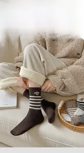 Detail of warm wool blend socks with cute animal embroidery and white stripes in dark brown