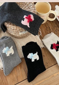 Detail of wool socks featuring plush Westie puppy patch and velvet bow accents