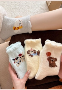 Detail of soft coral fleece socks featuring cute cartoon animal embroidery and wavy cuffs