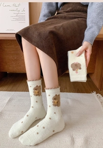 Detail of plush cream thermal socks with bear patterns and brown dots for winter warmth