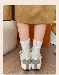 Detailed close-up of knitted beige socks featuring 'egg' tag and speckled yarn texture