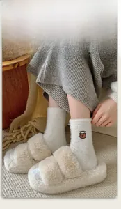 Dettaglio calzini invernali beige con ricamo a orsetto e pantofole calde in peluche