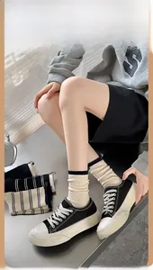 Detail of beige striped crew socks styled with black canvas sneakers and a thick rubber sole