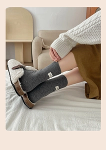 Detailed close-up of dark grey knitted socks with egg label and fuzzy white clogs