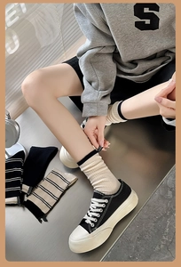 Detail of ribbed cotton mid-calf socks with striped cuffs and minimalist brand labels