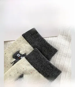 Detailed close-up of high-elasticity grey rib cuff on cute cartoon cat knit socks