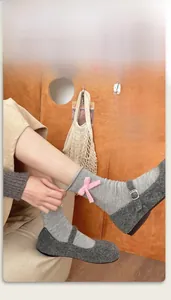 Dettaglio di calze grigie in maglia con fiocco rosa e scarpe stile Mary Jane