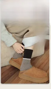 Detail of warm wool socks with brown ribbed stripes styled with suede platform mules