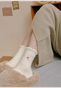 Dettaglio della calza termica in peluche bianco con ricamo di cane e bordo in pizzo