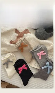 Dettaglio calzini in maglia con fiocchi 3D e bordi arrotolati in vari colori