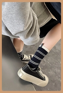 Detailed close-up of black and white striped ribbed crew socks for women on feet