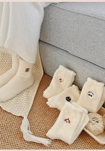 Dettaglio di calzini termici bianchi in peluche con ricami di animali e trama soffice