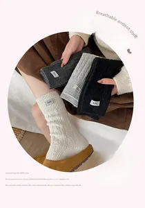 Detail of ribbed wool blend socks with egg label in ivory, grey, and black tones