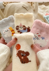 Close-up of cute cartoon plush socks in cream and pink with cozy fleece texture