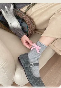 Dettaglio di calzini in cotone grigio a coste con fiocco rosa e scarpe Mary Jane