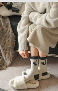 Close-up of knit crew socks featuring a cute black cat pattern and flecked grey texture
