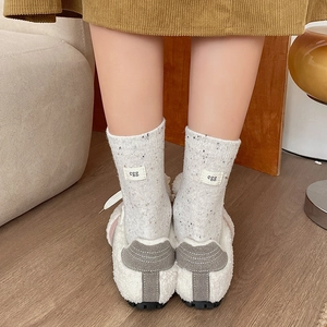 Light gray speckled crew socks with egg label detail worn with white fuzzy loafers