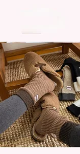 Close-up of brown patchwork knit socks with letter embroidery and fabric label detail