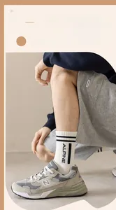Close-up of white combed cotton socks featuring black stripes and ALPINE lettering detail