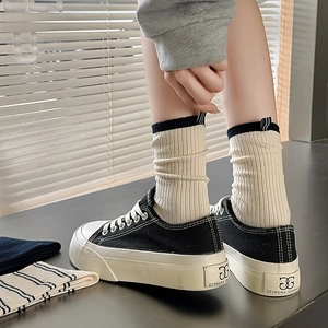 Classic black canvas platform shoes with beige ribbed crew socks featuring contrast stripe