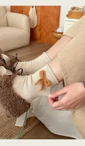 Dettaglio di calze beige a coste con un grazioso fiocco arancione e una trama morbida