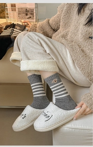 Detailed close-up of grey and white striped wool socks with cute dog embroidery detail