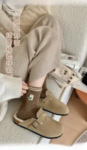 Dettaglio di calzini soffici marrone caffè con ricamo orso e sabot color kaki