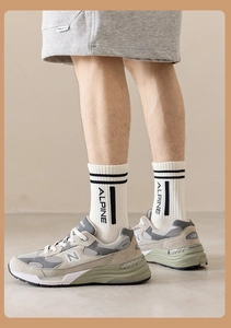 Detail of white cotton athletic crew socks with black stripes and Alpine lettering on top