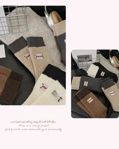 Detail of embroidered mid-calf socks with letter patch in beige, khaki and grey tones