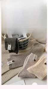 Détail de chaussettes en laine avec texture côtelée, étiquette tissu et bouton en bois