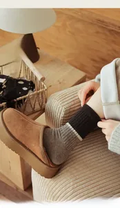 Detail of women's thick-soled brown suede slippers and warm striped wool knit socks