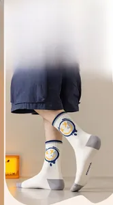 Détail de chaussettes en coton blanc avec smiley graffiti jaune et éclaboussures bleues