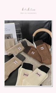 Close-up of color-block knit mid-calf socks with 'attends' letter embroidery patches