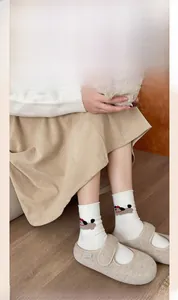 Close-up of white wool socks with cute cartoon puppy pattern and rolled edges on floor